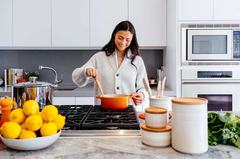 Mujer cocinando en una cocina blanca con cubierta de mármol